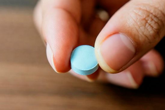Синяя таблетка Рука держит синюю таблетку